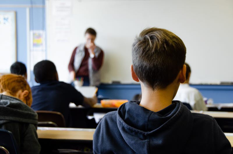 ryggen på en elev längst bak i ett klassrum