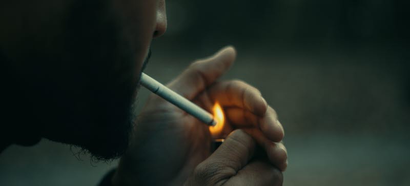 Man som tänder en cigarett, sedd snett bakifrån
